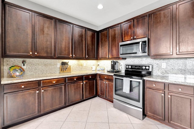 kitchen with dark brown cabinetry, appliances with stainless steel finishes, and light stone countertops