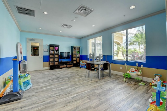 rec room with ornamental molding and light hardwood / wood-style floors