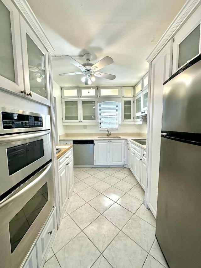 kitchen featuring appliances with stainless steel finishes, ceiling fan, sink, light tile patterned floors, and white cabinetry