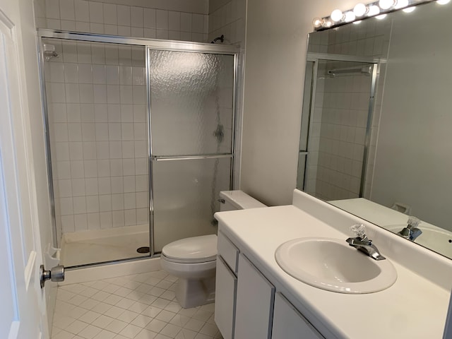 bathroom with tile patterned flooring, vanity, a shower with shower door, and toilet