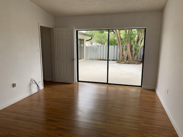 spare room featuring a textured ceiling, dark hardwood / wood-style flooring, and lofted ceiling