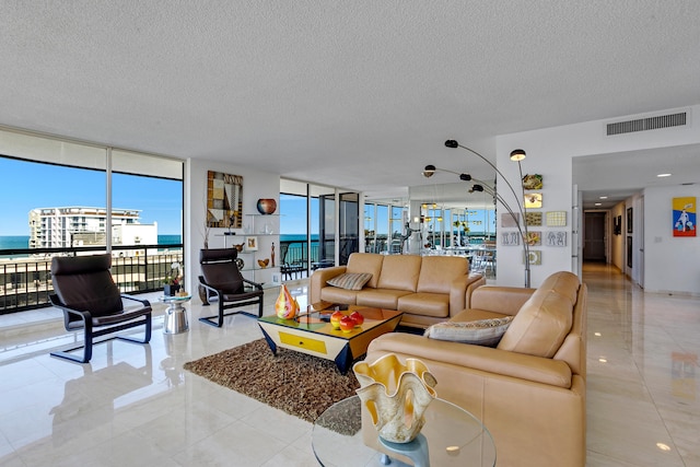 living room with a textured ceiling, a water view, and a wall of windows