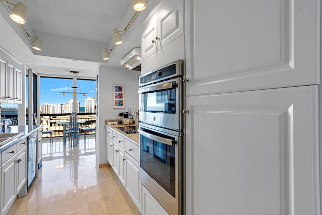 kitchen with white cabinets, expansive windows, rail lighting, a textured ceiling, and double oven