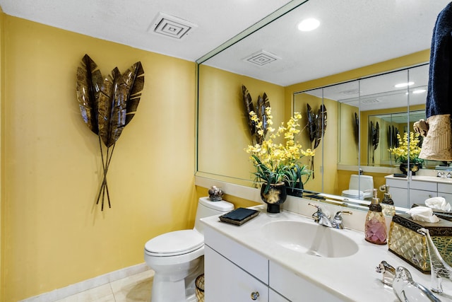 bathroom with toilet, a textured ceiling, vanity, and tile patterned floors