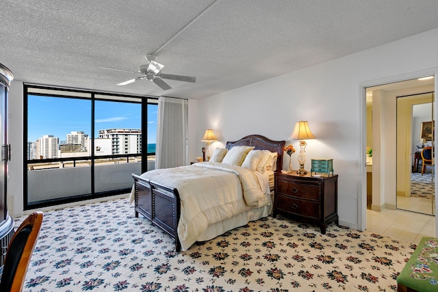 bedroom with ceiling fan, floor to ceiling windows, access to exterior, and a textured ceiling