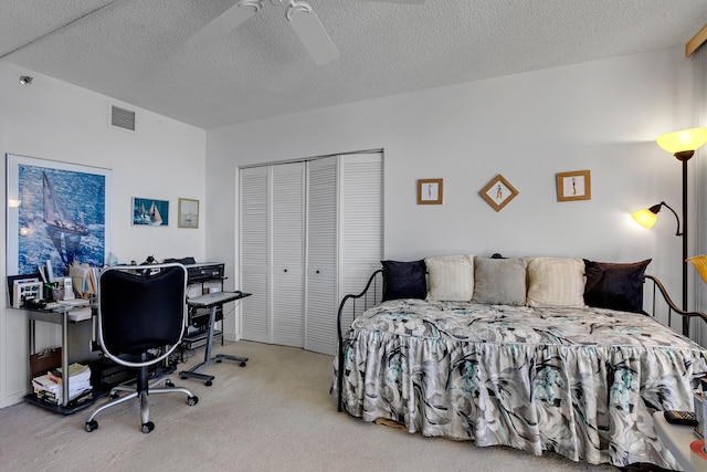 bedroom featuring ceiling fan, a closet, light carpet, and a textured ceiling