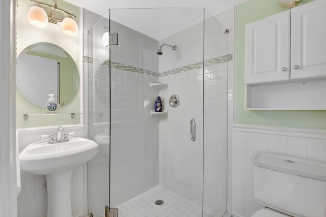 bathroom featuring toilet, a shower with shower door, and sink