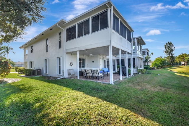 back of property featuring a sunroom, an outdoor hangout area, a yard, central AC, and a patio area