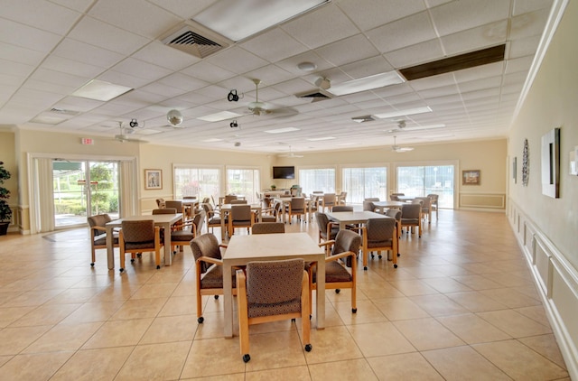 dining area featuring ceiling fan, a drop ceiling, and light tile patterned flooring