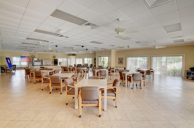 dining room featuring light tile patterned floors, a drop ceiling, and ceiling fan