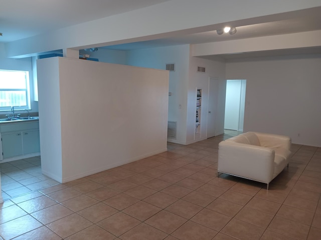 unfurnished living room featuring light tile patterned floors and sink