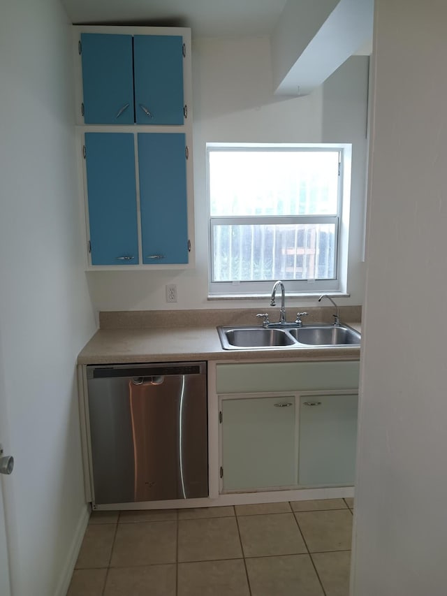 kitchen featuring stainless steel dishwasher, light tile patterned floors, sink, and blue cabinets