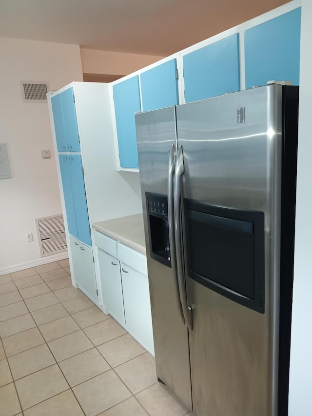 kitchen with white cabinets, light tile patterned flooring, and stainless steel refrigerator with ice dispenser