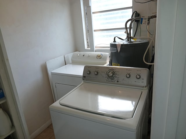 laundry room featuring water heater, washer and clothes dryer, and light tile patterned floors