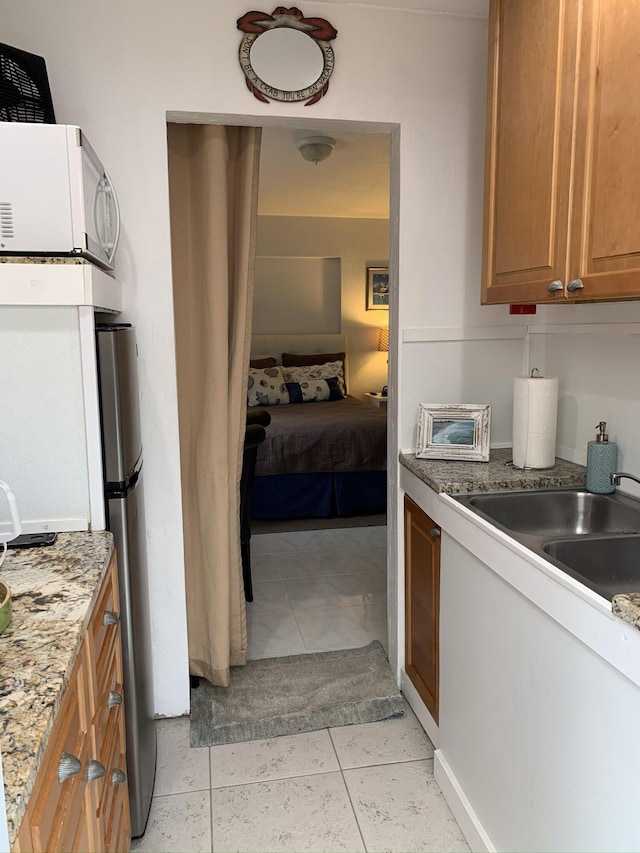 kitchen with light stone counters, light tile patterned floors, and sink