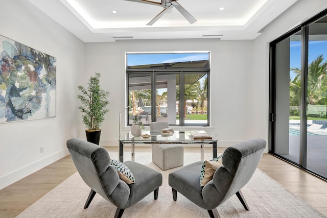 office area featuring a tray ceiling, ceiling fan, french doors, and light hardwood / wood-style floors