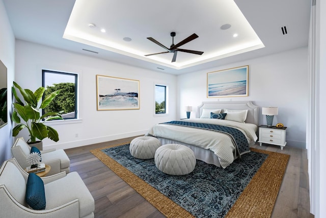 bedroom with a tray ceiling, ceiling fan, and dark wood-type flooring