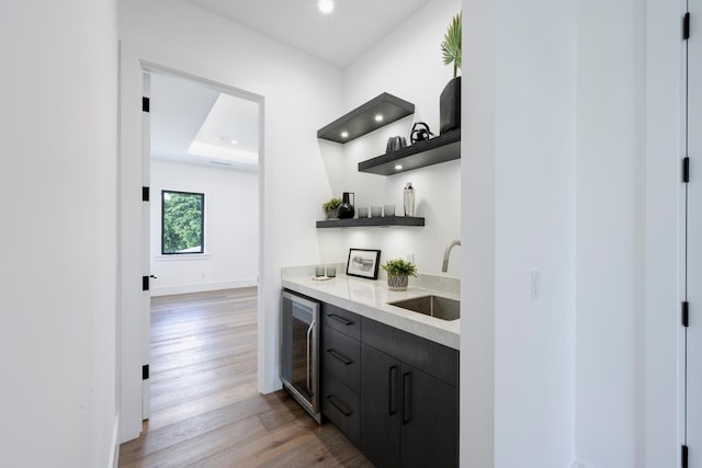 bar featuring wood-type flooring, wine cooler, and sink