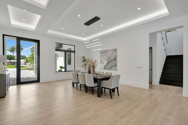 dining space featuring a tray ceiling and light hardwood / wood-style floors