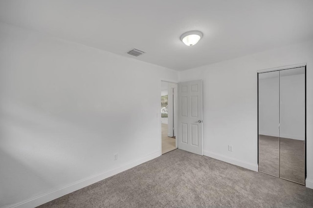 unfurnished bedroom with light colored carpet and a closet