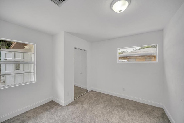 unfurnished bedroom with light carpet and a closet