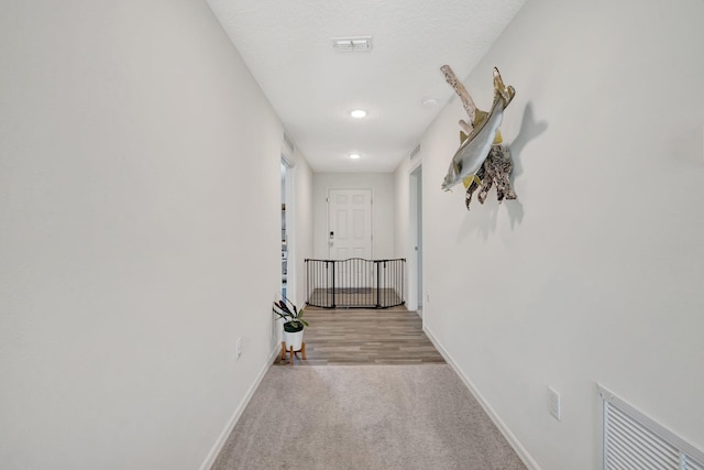 hallway featuring visible vents, baseboards, carpet, and a textured ceiling