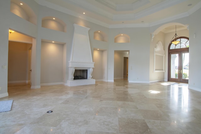 unfurnished living room featuring ornamental molding, a fireplace, a high ceiling, and french doors