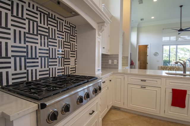 kitchen featuring sink, backsplash, kitchen peninsula, stainless steel gas stovetop, and ornamental molding