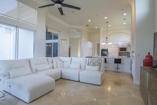 living room featuring ceiling fan, crown molding, a high ceiling, and sink