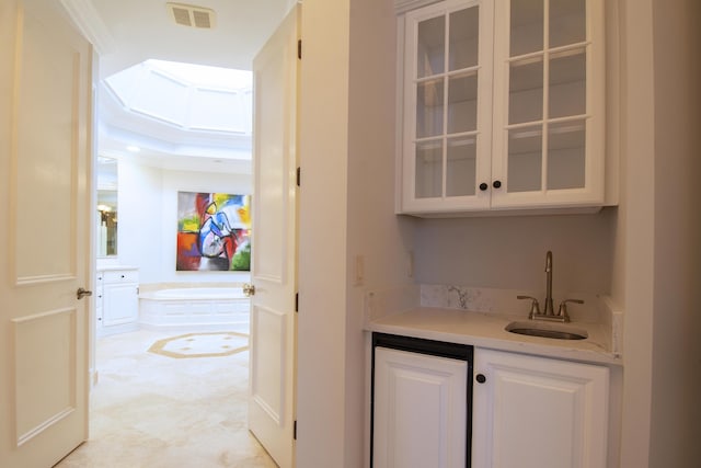 bar featuring white cabinets, crown molding, and sink