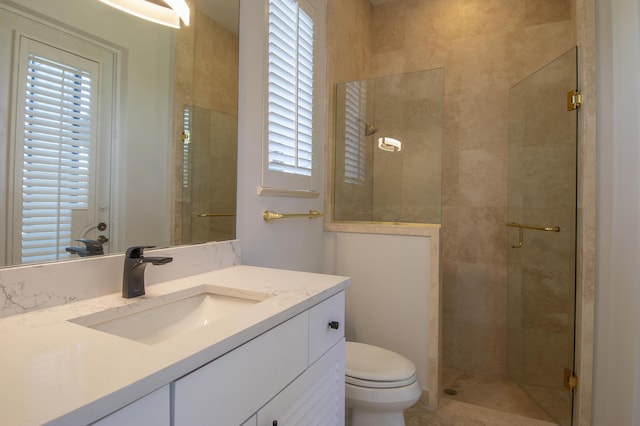 bathroom featuring a shower with door, vanity, and toilet