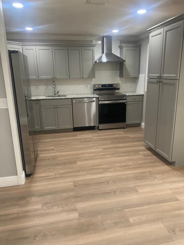 kitchen featuring gray cabinets, appliances with stainless steel finishes, wall chimney exhaust hood, sink, and light hardwood / wood-style flooring