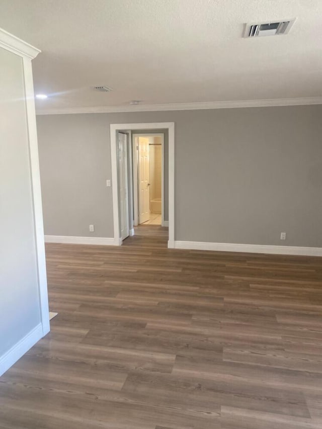 unfurnished room featuring a textured ceiling, ornamental molding, and dark wood-type flooring