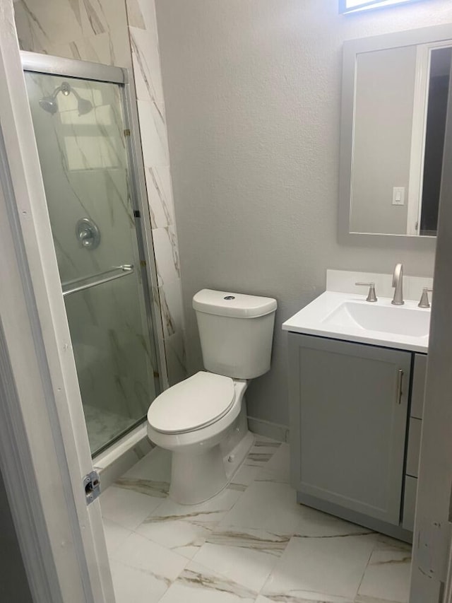 bathroom featuring toilet, a shower with shower door, and vanity