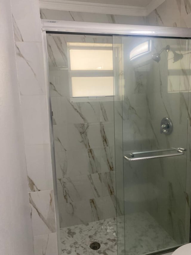 bathroom featuring a shower with door and crown molding