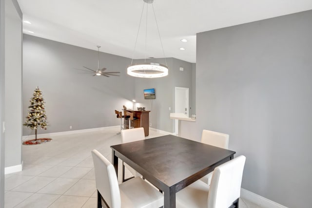 dining space featuring a towering ceiling, light tile patterned floors, and ceiling fan with notable chandelier