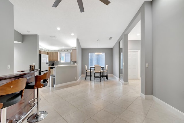 interior space featuring light tile patterned floors, light brown cabinets, white fridge, and ceiling fan