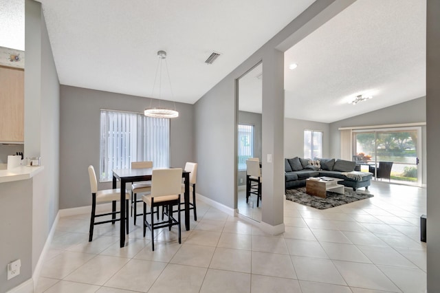 dining room featuring a chandelier, light tile patterned floors, a textured ceiling, and vaulted ceiling