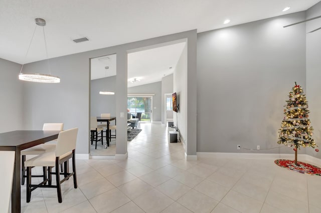 tiled dining area with vaulted ceiling and a notable chandelier