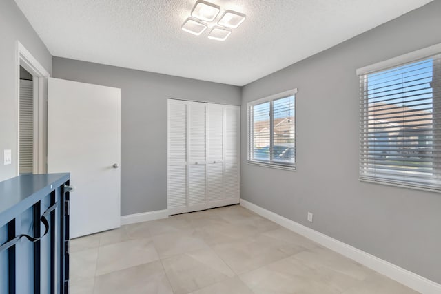 unfurnished bedroom with light tile patterned floors, a textured ceiling, and a closet