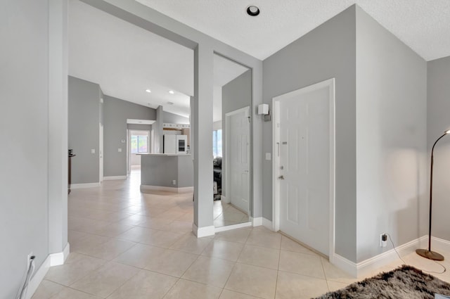 tiled foyer entrance featuring a textured ceiling and vaulted ceiling