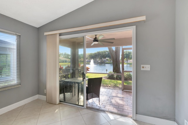 doorway to outside featuring a water view, light tile patterned floors, a wealth of natural light, and vaulted ceiling