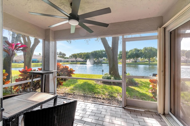 sunroom / solarium featuring a water view and ceiling fan