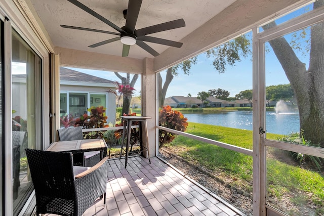 sunroom featuring ceiling fan and a water view