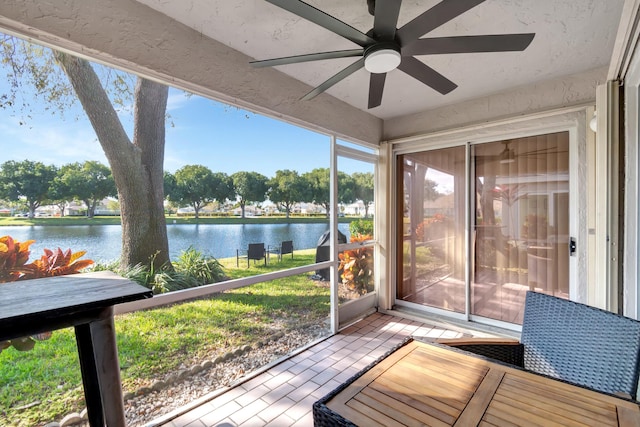 unfurnished sunroom featuring ceiling fan and a water view