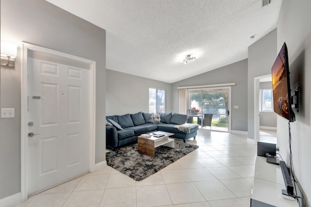 living room featuring a textured ceiling, lofted ceiling, and light tile patterned flooring