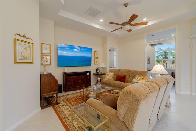 tiled living room featuring a raised ceiling and ceiling fan