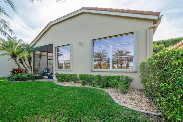 rear view of property featuring a sunroom and a lawn