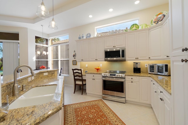 kitchen featuring appliances with stainless steel finishes, light stone counters, hanging light fixtures, and sink