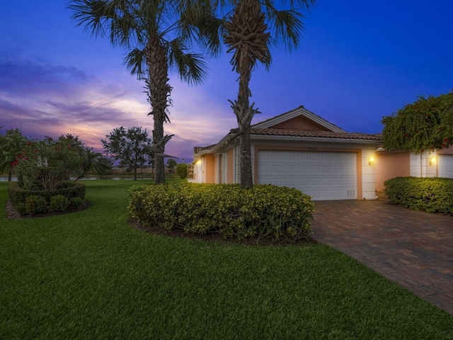 property exterior at dusk with a lawn and a garage